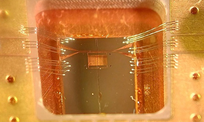 This is an alumina-encapsulated V[TCNE]ₓ device integrated into a microwave superconducting resonator chip, shown as it is being loaded into a sub-Kelvin cryogenic refrigerator. The dark brown vertical strip on the chip is the alumina layer.