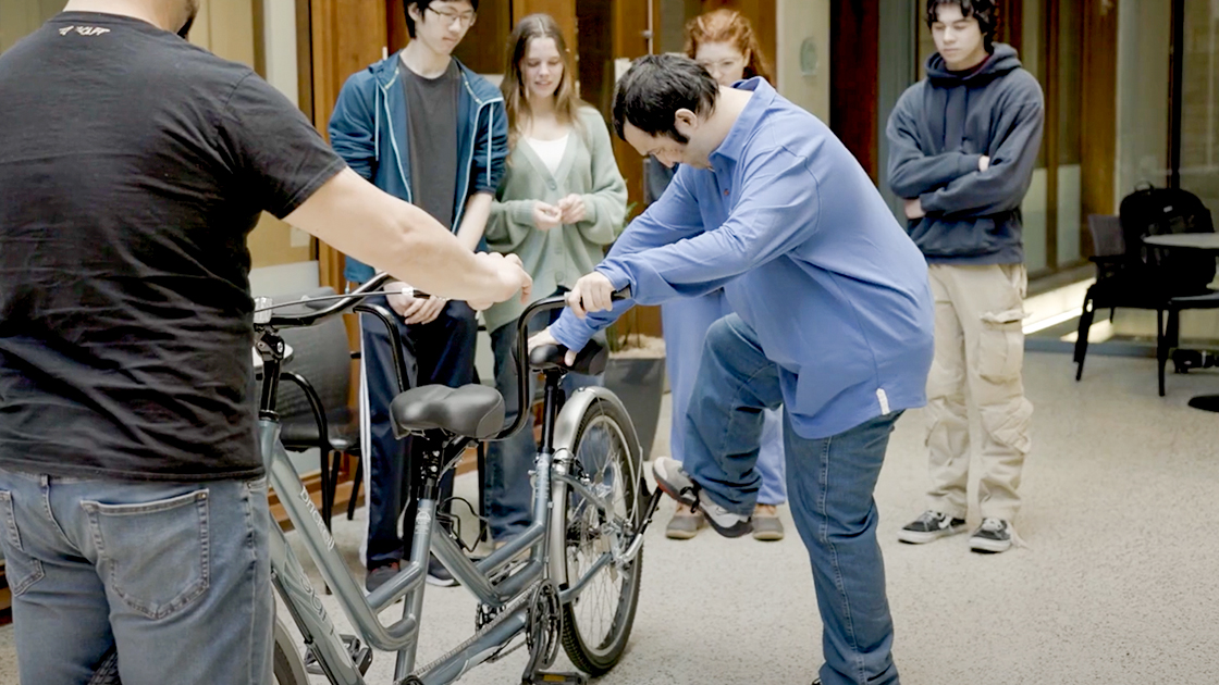 Student engaging the kickstand on a bike.